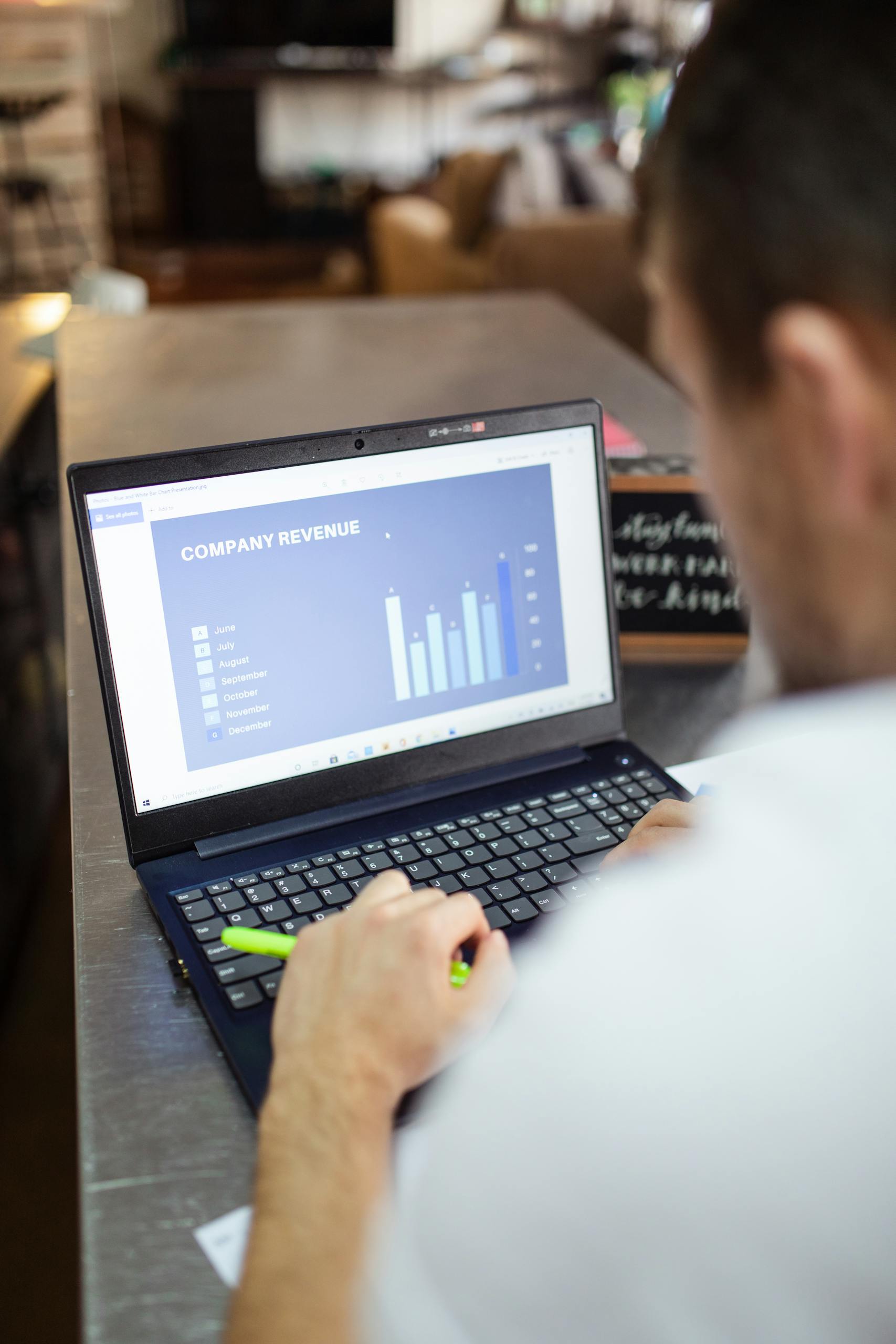 Man reviewing company revenue charts on a laptop indoors