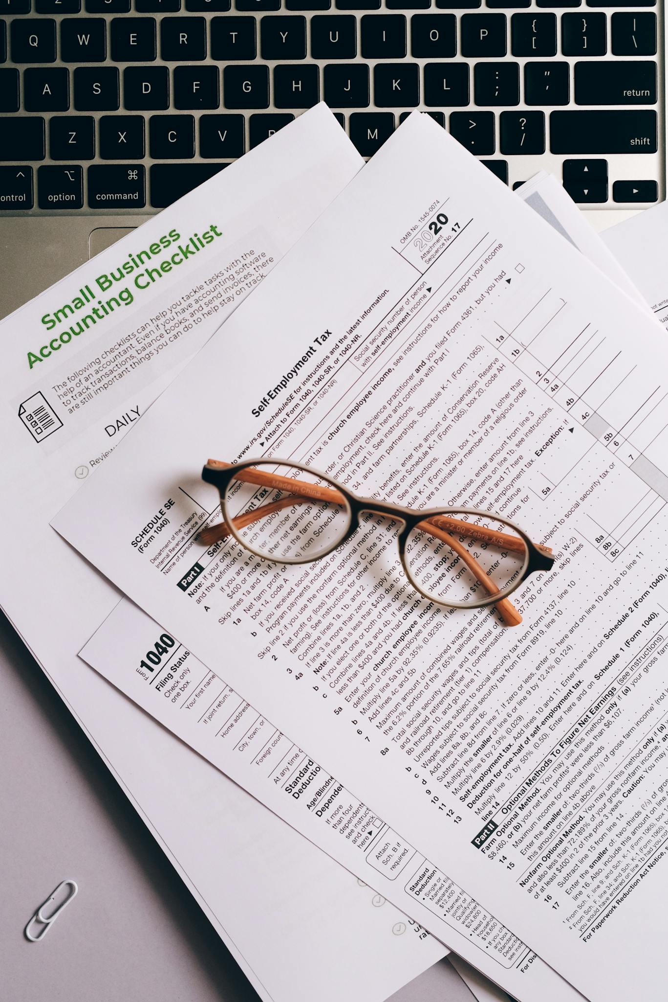 Overhead view of tax documents and eyeglasses on a laptop keyboard