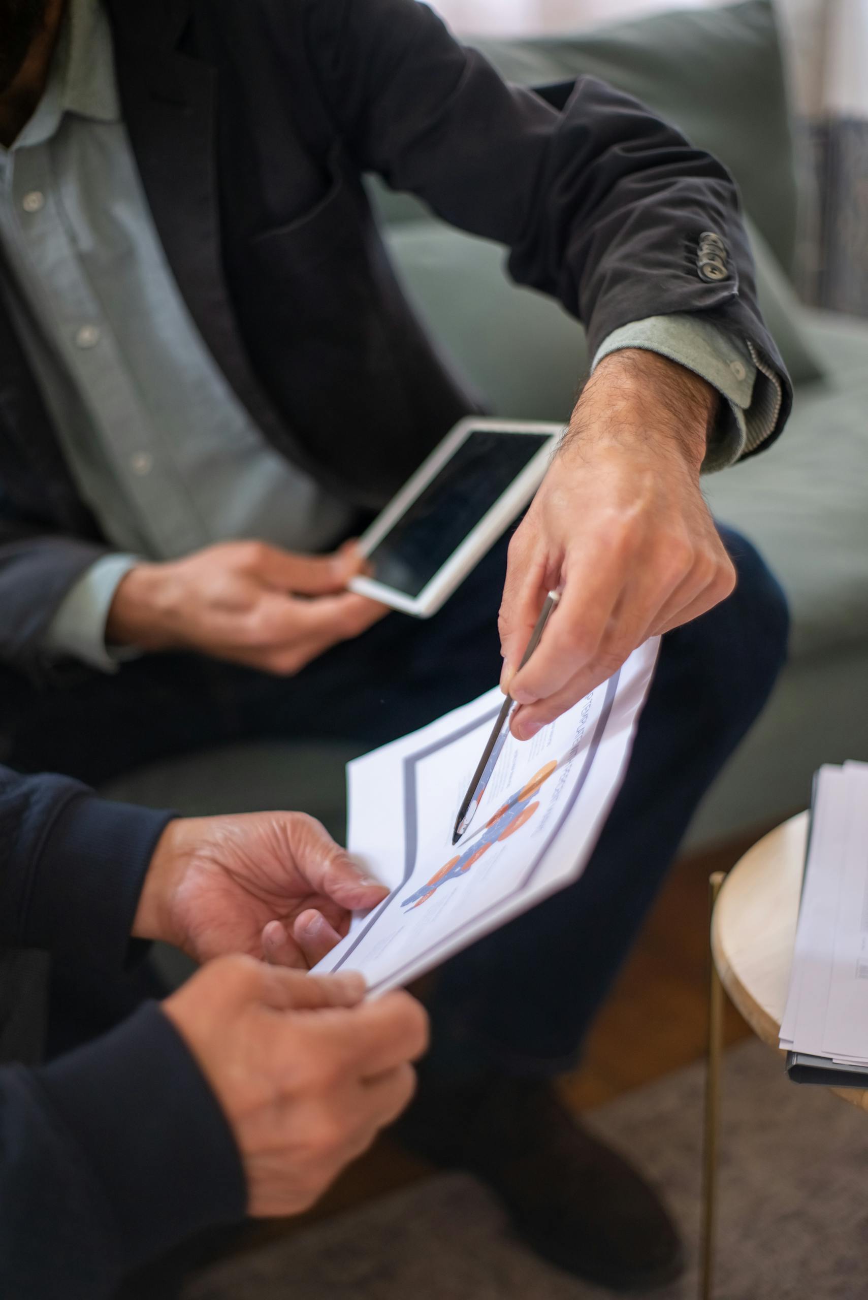 Two professionals in a business meeting discussing documents and a tablet